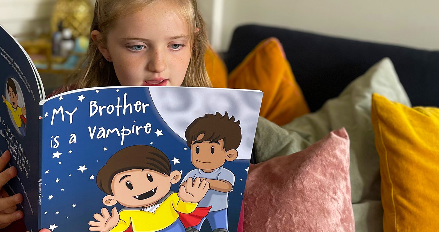 A child reading "My brother is a Vampire" on a sofa