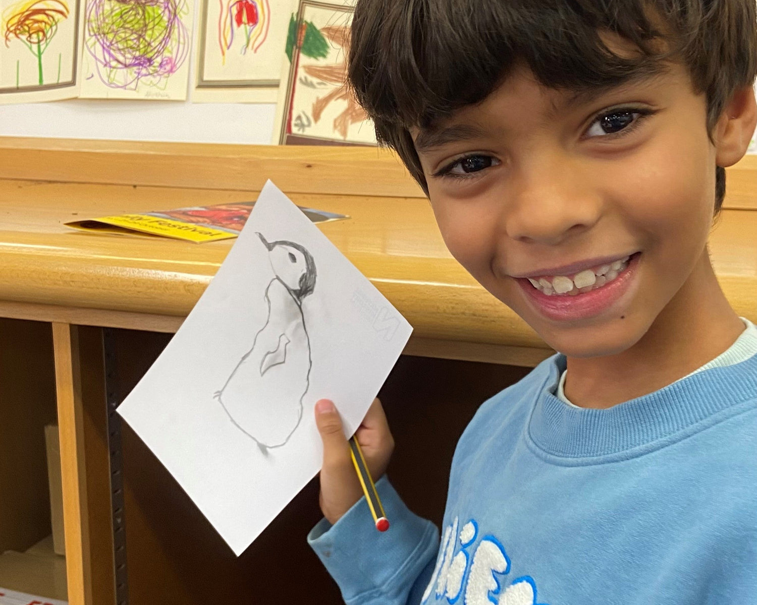 Child holding a drawing with a display of cards in the background